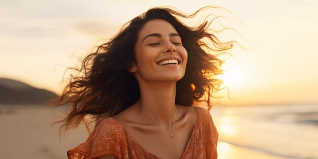 Una deliziosa dama latina con gli occhi chiusi si gode il tramonto su una spiaggia con i capelli accarezzati dal vento