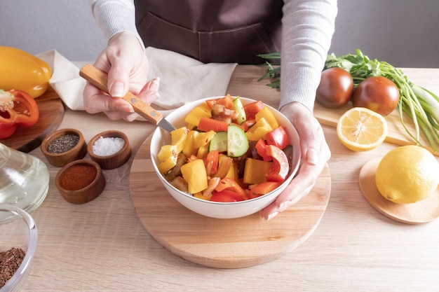 Una deliziosa insalata dietetica biologica di verdure fresche in una grande ciotola la mano della ragazza tiene una forchetta con pezzi di lattuga