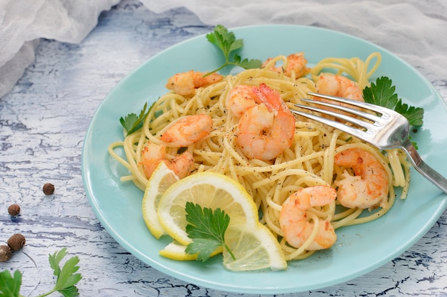 Una deliziosa ricetta per spaghetti con gamberi, decorata con limone e prezzemolo.