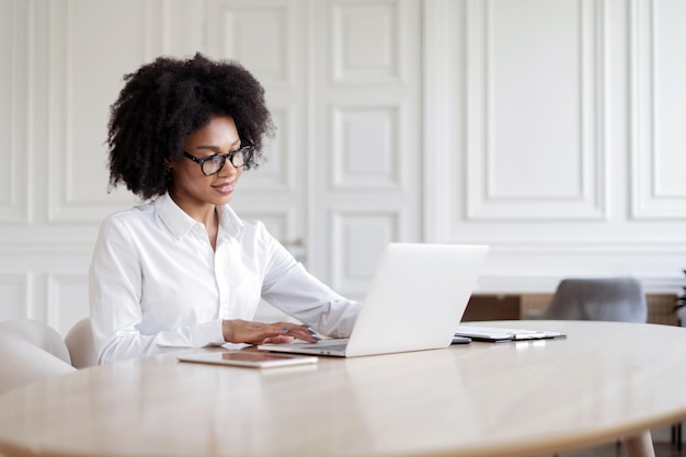 Una designer freelance donna con gli occhiali che lavora in ufficio stampa un messaggio per il cliente