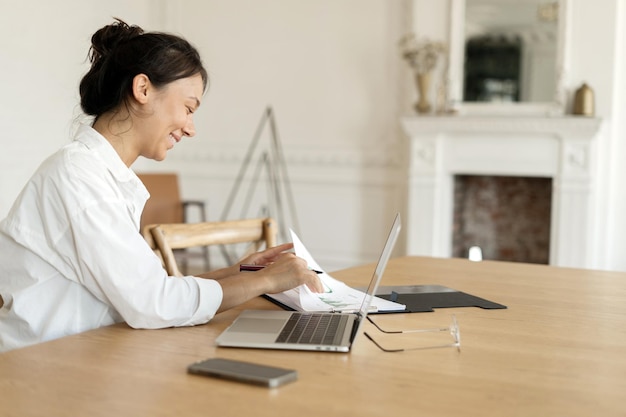 Una designer freelance femminile che lavora a casa fa un report sul posto di lavoro in ufficio