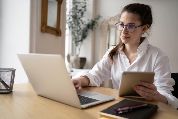 Una designer freelance femminile sta lavorando a un progetto online Utilizza un posto di lavoro portatile in ufficio