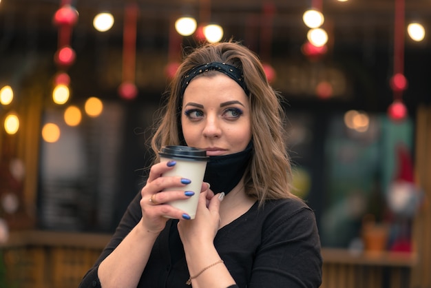 Una dolce femmina di aspetto caucasico con una maschera nera, si siede e lavora in un Internet cafè