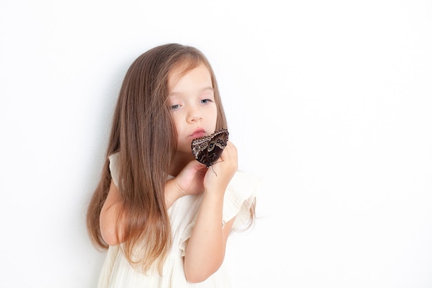 Una dolce ragazza tiene tra le mani una farfalla morpho e la esamina. Sfondo bianco, spazio per il testo. Lo studio della natura. Rispetto. Foto di alta qualità