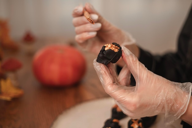 Una dolciera decora di oro le caramelle a forma di teschi neri per Halloween