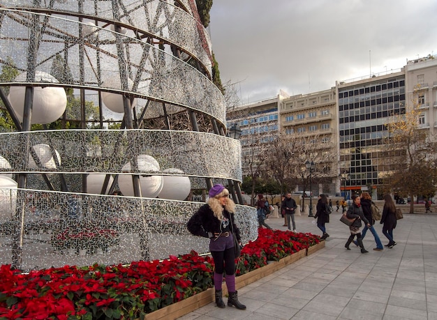 Una donna a Capodanno e albero di Natale sulla piazza centrale Syntagma posa per una foto ad Atene, in Grecia