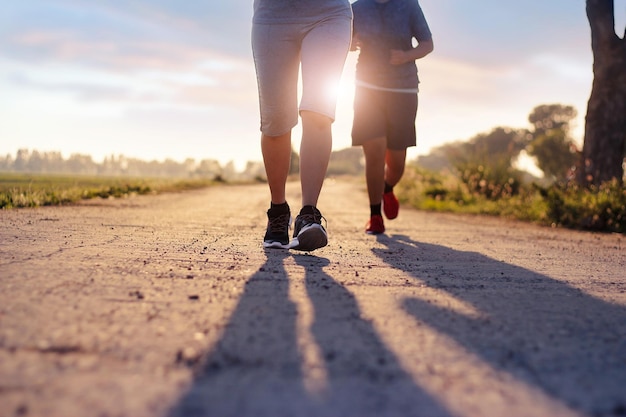 Una donna a due corridori sta correndo e facendo jogging un allenamento all'aperto sulla strada rurale sullo sfondo del tramonto