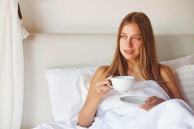 Una donna a letto con una tazza di caffè