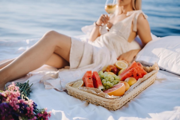 Una donna a letto riposa in riva al mare con un bicchiere di champagne e frutta