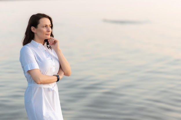 Una donna abbastanza matura si trova sulla spiaggia e guarda pensierosa in lontananza in mare