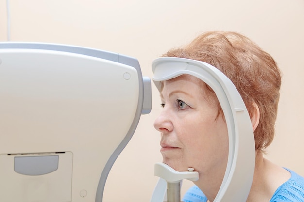 Una donna adulta a un appuntamento con un oftalmologo controlla la sua visione con uno speciale apparecchio Closeup