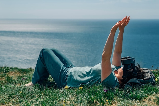 Una donna adulta giace su una montagna sullo sfondo del mare in estate primavera in virtuale