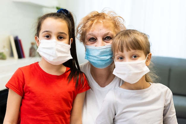 una donna adulta, una nonna in pensione con nipoti che indossano una mascherina medica in quarantena domestica, a causa del COVID-19.