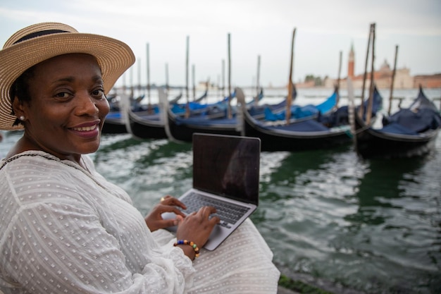 Una donna africana matura usa il suo laptop mentre si trova a Venezia in Italia