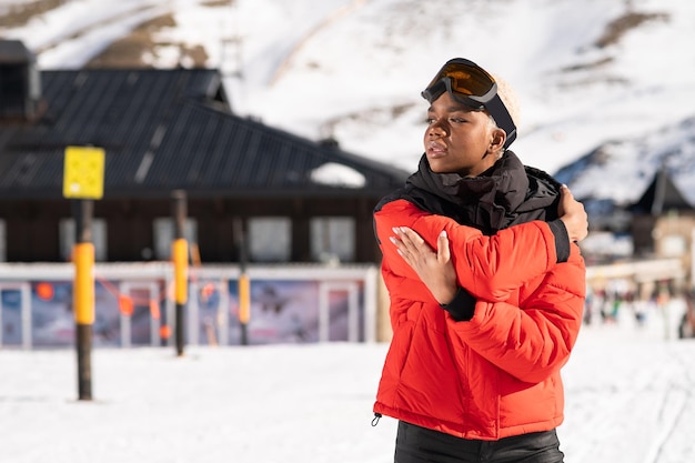 Una donna afroamericana che indossa occhiali da neve su una montagna innevata durante l'inverno