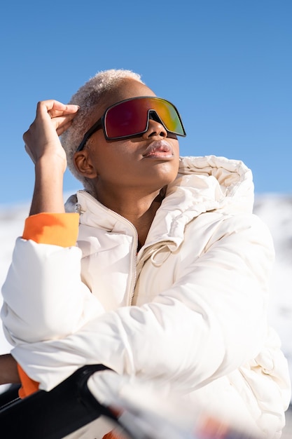 Una donna afroamericana che indossa occhiali da neve su una montagna innevata durante l'inverno