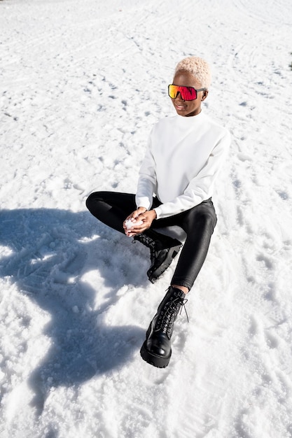 Una donna afroamericana che indossa occhiali da neve su una montagna innevata durante l'inverno