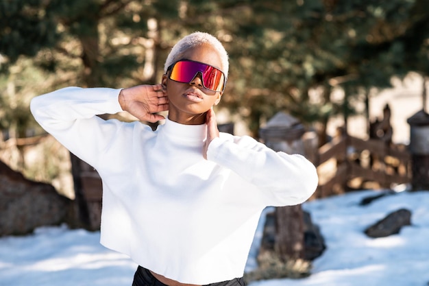 Una donna afroamericana che indossa occhiali da neve su una montagna innevata durante l'inverno