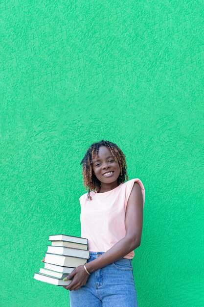 Una donna afroamericana felice sorridente tiene una pila di libri Istruzione Torna a scuola