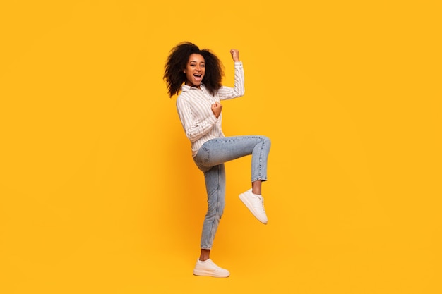 Una donna afroamericana gioiosa che balla su uno sfondo giallo