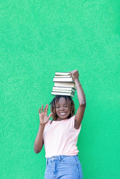 Una donna afroamericana sorridente tiene una pila di libri Istruzione Ritorno a scuola