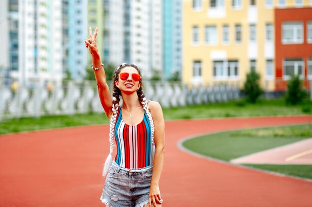 Una donna alla moda in occhiali da sole posa allegramente sullo sfondo dello stadio.