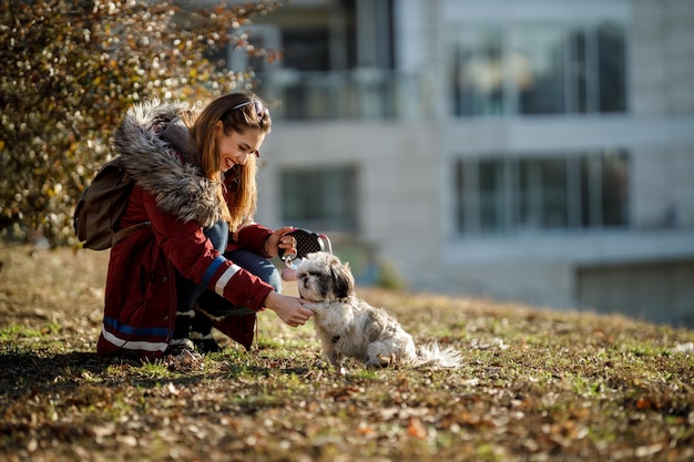 Una donna allegra che gioca con il suo simpatico cucciolo di Shih Tzu al parco cittadino.