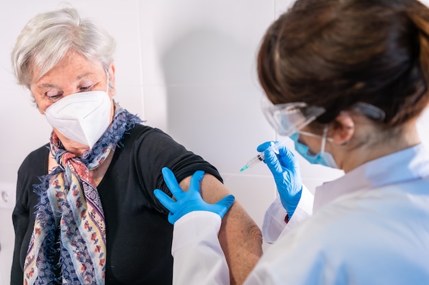 Una donna anziana che riceve l'iniezione del vaccino contro il coronavirus da un medico per ricevere gli anticorpi, immunizza la popolazione.