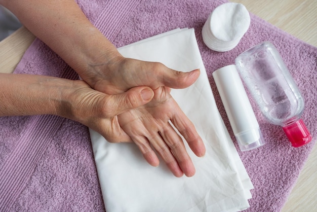 Una donna anziana con l'artrite si fa un massaggio alle mani usando una crema