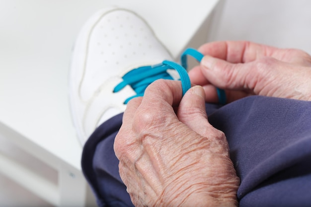 Una donna anziana di 80 anni stringe i lacci delle scarpe sulle sue calzature