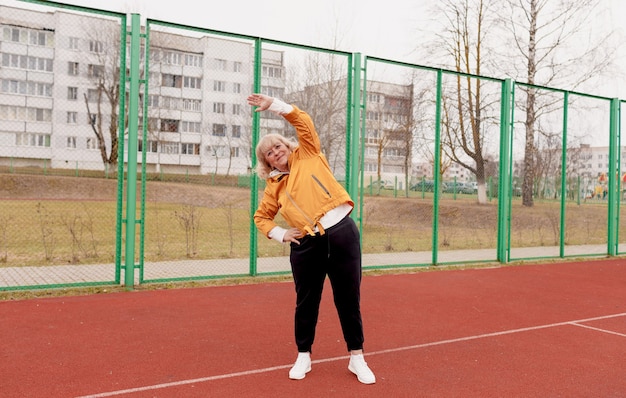 Una donna anziana fa esercizi nello stadio sul tapis roulant rosso. uno stile di vita sano