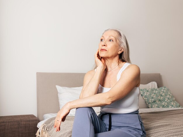 Una donna anziana frustrata seduta su un letto nel soggiorno