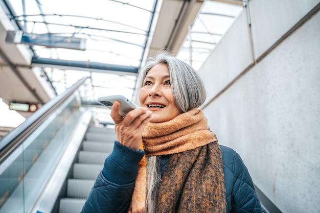 Una donna anziana in una stazione di trail usa il suo smartphone