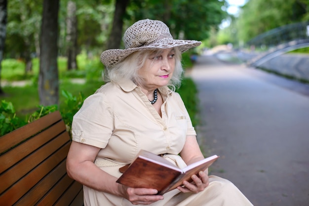 Una donna anziana legge un libro nel parco