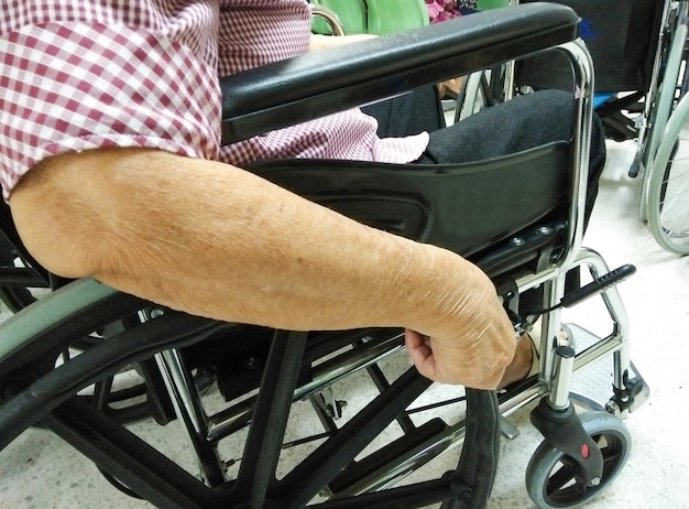 Una donna anziana o anziana è seduta su una sedia a rotelle e tiene la mano sulla ruota della sedia a rotelle