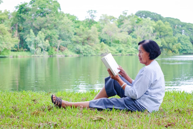 Una donna anziana seduta e leggendo un libro in un parco Vita felice dopo la pensione