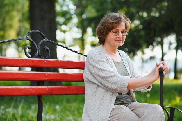 Una donna anziana seduta su una panchina nel parco estivo
