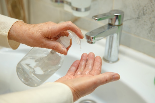 Una donna anziana si disinfetta le mani in bagno