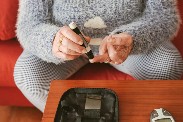 Una donna anziana si punge il dito per prelevare il sangue per un test di salute della glicemia