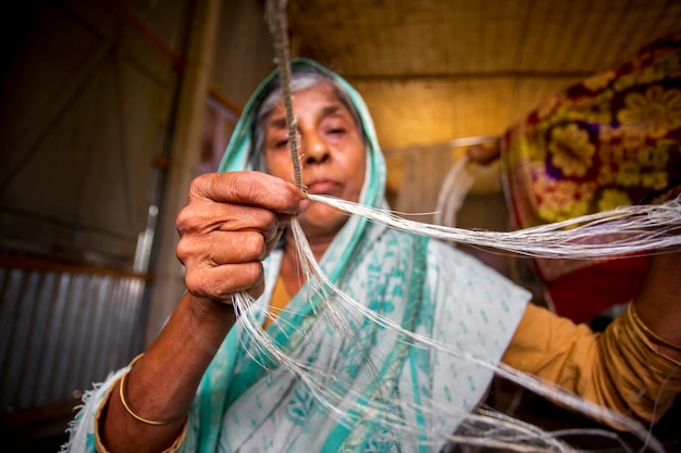 Una donna anziana sta facendo sulle sue mani magre una corda dalla fibra del banano a Madhupur Tangail Bangladesh