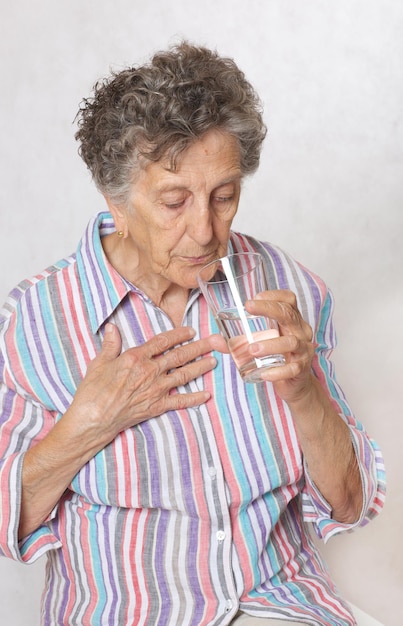 Una donna anziana tra i 70 e gli 80 anni beve dell'acqua