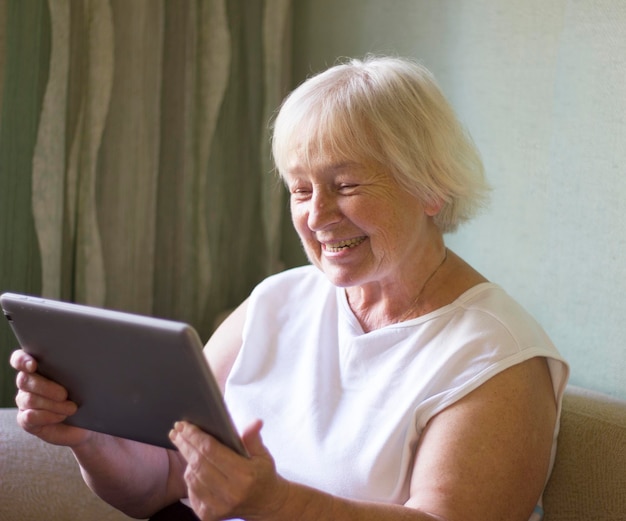 Una donna anziana un pensionato comunica su un tablet e un telefono