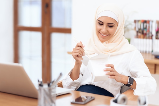 Una donna araba in un hijab sta pranzando.