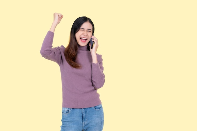 Una donna asiatica allegra sta parlando al telefono facendo una chiamata a qualcuno con gioia