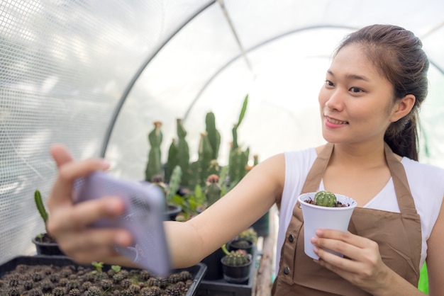 Una donna asiatica ama fare giardinaggio con i cactus ed è proprietaria di una start-up che vende alberi online.