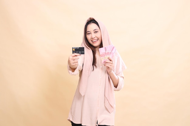 Una donna asiatica con un'espressione sorridente che ride di te tenendo la tua carta di debito davanti a te e Carr