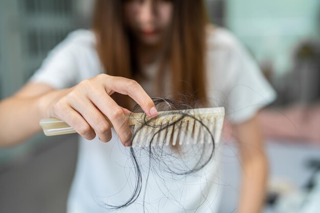 Una donna asiatica ha problemi con la caduta dei capelli lunghi e si attacca alla spazzola a pettine