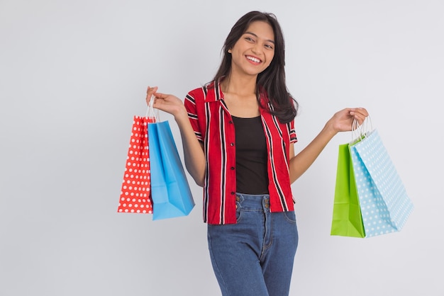 Una donna asiatica in piedi con un sacco di shopping bag in mano su sfondo isolato