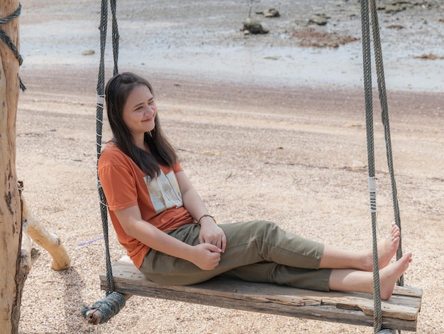 Una donna asiatica oscilla su un'altalena in spiaggia durante una vacanza nel sud della Thailandia.