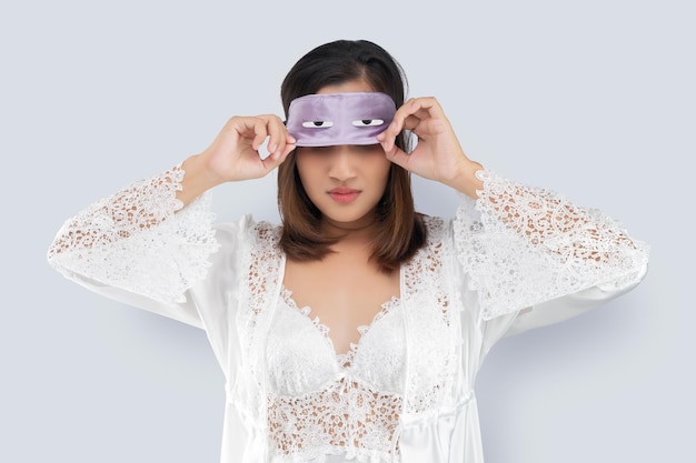 Una donna asiatica si toglie una maschera da sonno.